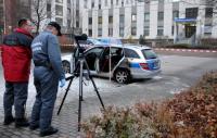 Zwei Kriminaltechniker untersuchen den durch den Brandanschlag beschädigten Streifenwagen vor dem Polizeirevier in Neustadt