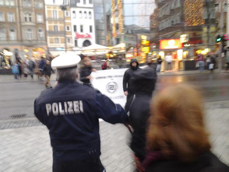 Angriff auf die Demo. Im Hintergrund das Banner mit dem Logo der faschistischen "Goldenen Morgenröte".