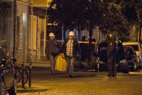 Polizisten in Zivil sammeln die Steine als Beweisstücke ein - vorsichtshalber mit Helm auf dem Kopf. Foto: ABIX