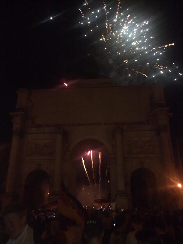 Bombenstimmung am Siegestor. „Zum Frieden mahnend“? Der Ausrauf „Auf den Sieg!“ zeigt, dass Deutschland eine geläuterte Nation ist, die nun eine zusätzliche Silbe inkauf nimmt, um „Sieg Heil!“ zu vermeiden.