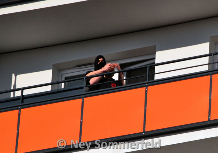 Neonazis auf einem Balkon beobachten den Spaziergang