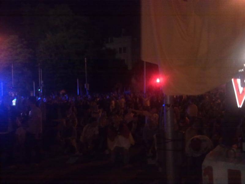 Fans umringen sitzend und jubelnd die gerade gehisste Flagge.