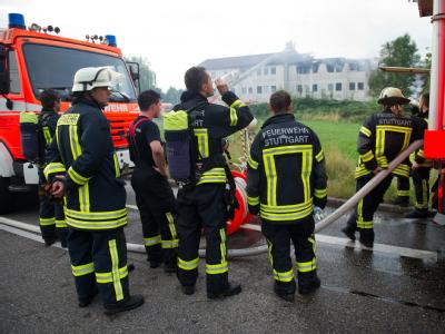 Feuerwehrleute haben sich vor dem brennenden Flüchtlingswohnheim versammelt.