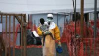 Paynesville, Liberia, 05.10.2014: Mitarbeiter mit Schutzanzug im MSF Ebola-Behandlungszentrum in Liberia trägt ein Kind, das möglicher Weise mit Ebola infiziert ist. © John Moore/Getty Images 